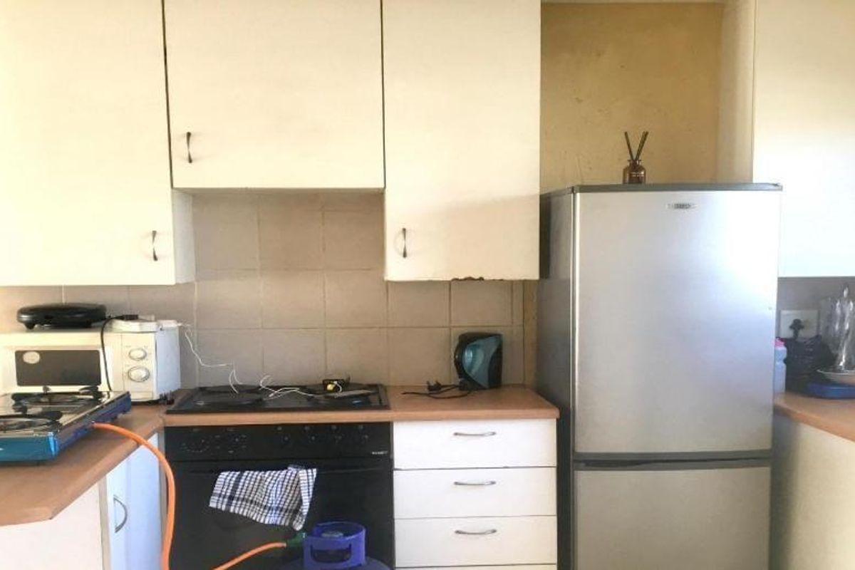 A functional kitchen featuring built-in cabinetry, laminate countertops, and a built-in oven, offering a practical layout with potential for cosmetic updates.
