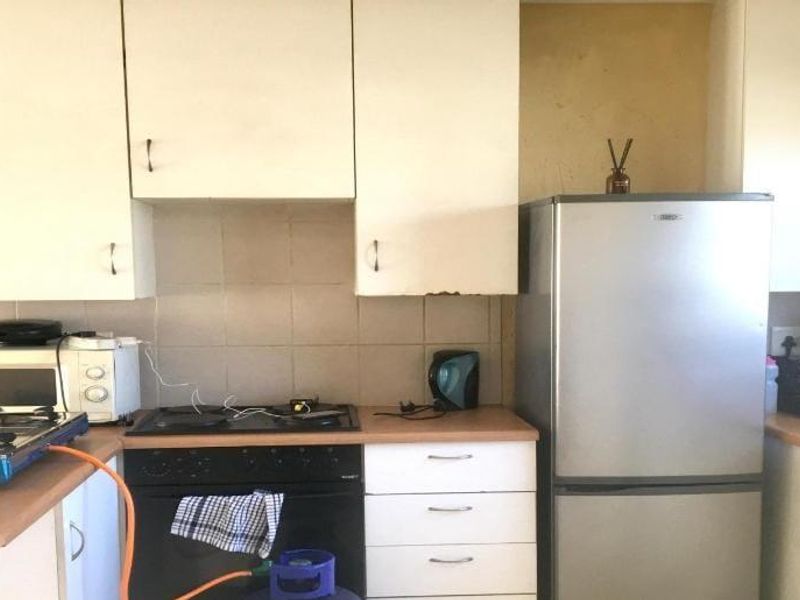 A functional kitchen featuring built-in cabinetry, laminate countertops, and a built-in oven, offering a practical layout with potential for cosmetic updates.