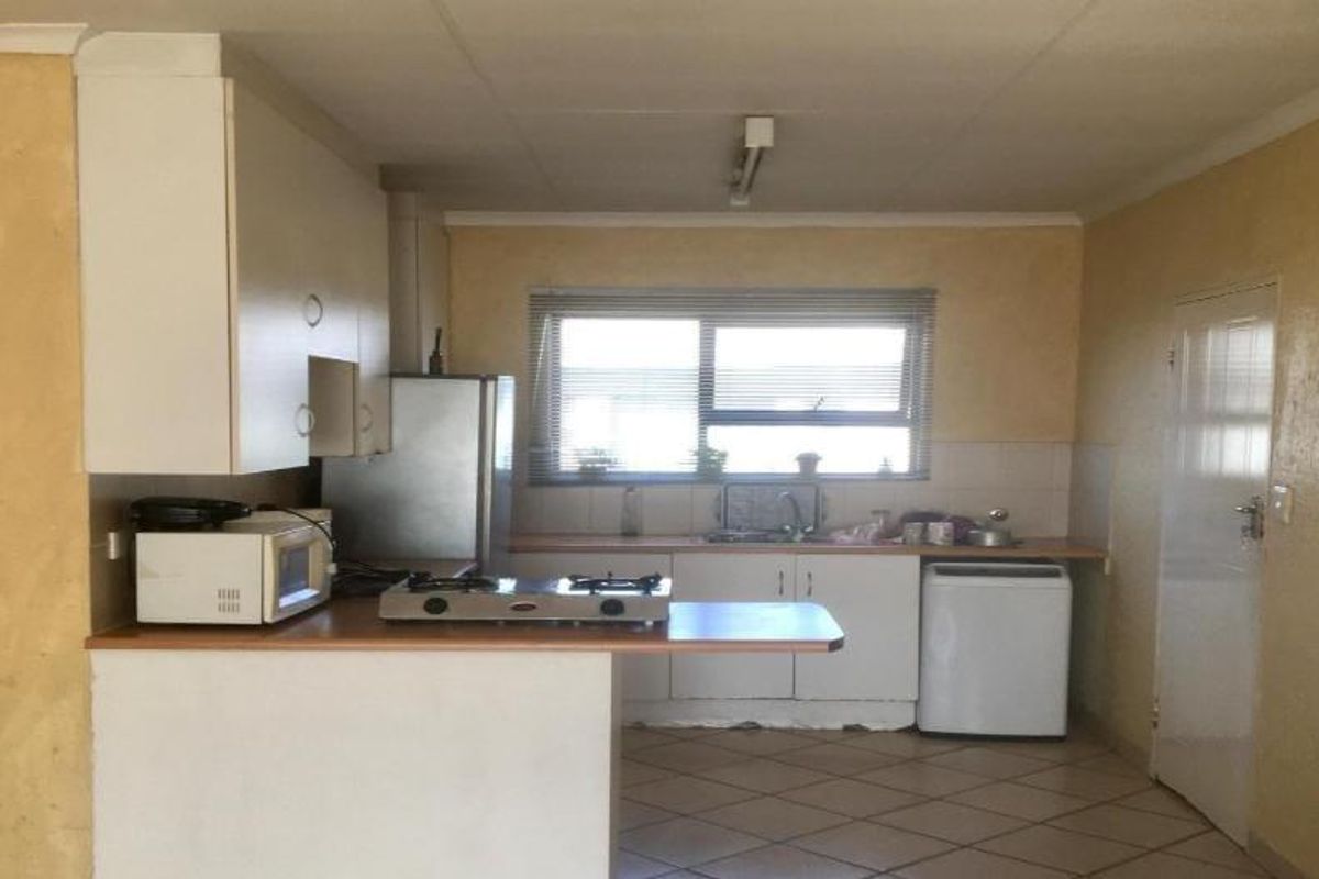 A functional kitchen featuring built-in cabinetry, laminate countertops, a gas hob, and tiled flooring, offering potential for modernization and cosmetic updates.