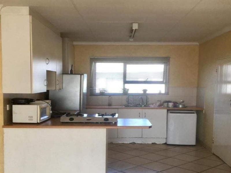A functional kitchen featuring built-in cabinetry, laminate countertops, a gas hob, and tiled flooring, offering potential for modernization and cosmetic updates.
