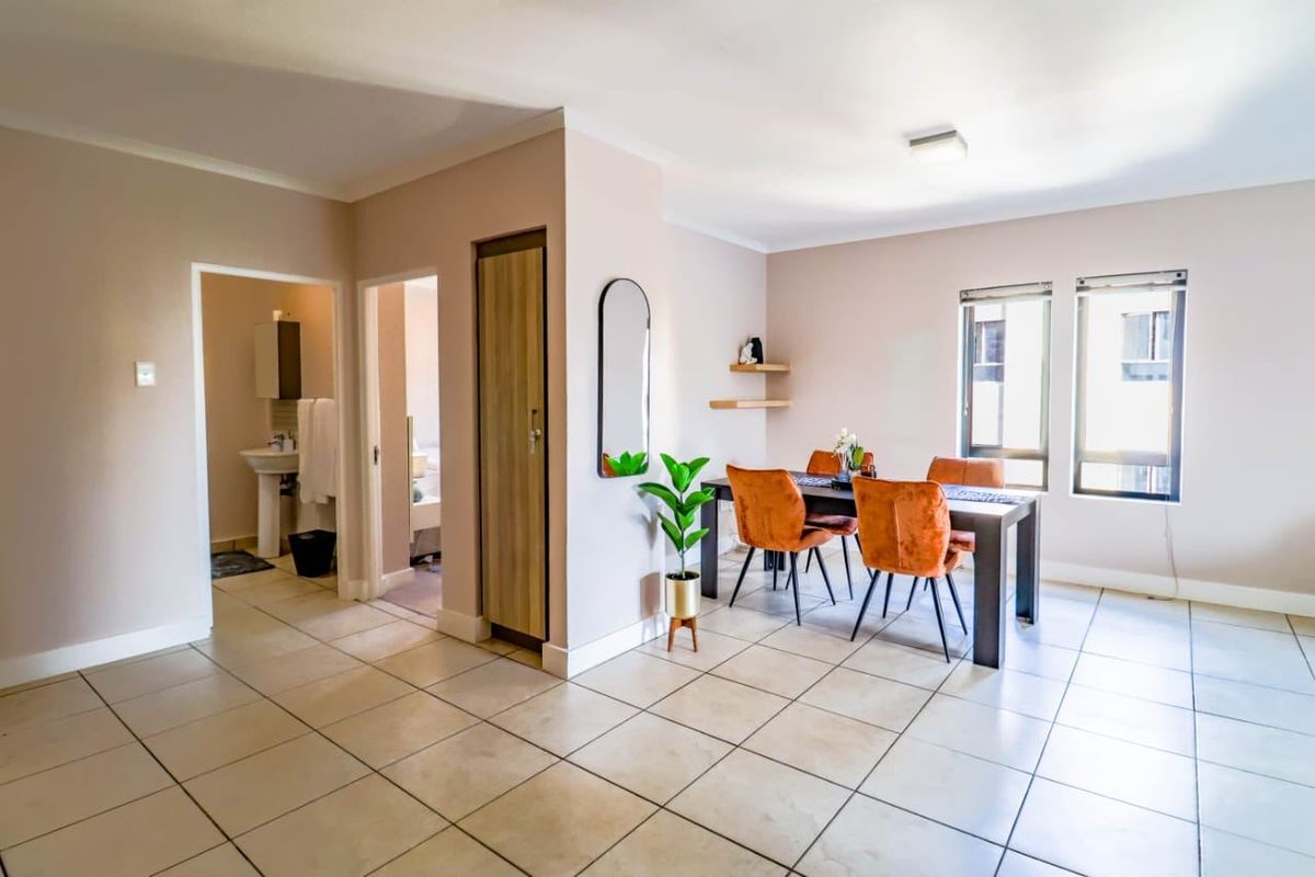 Open-plan living and dining area featuring neutral tiled flooring, built-in storage, and access to an adjacent bathroom.