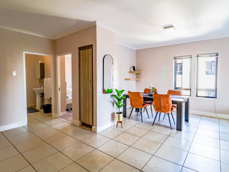 Open-plan living and dining area featuring neutral tiled flooring, built-in storage, and access to an adjacent bathroom.