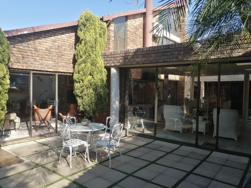 A paved outdoor patio area featuring brick construction, large sliding glass doors, and a built-in chimney, providing a seamless transition between indoor and outdoor living.