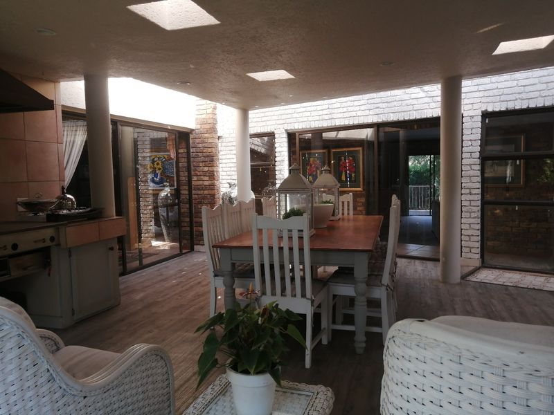 A spacious covered patio featuring exposed brick walls, skylights, and a built-in cooking area, seamlessly connecting to the interior through large sliding glass doors.