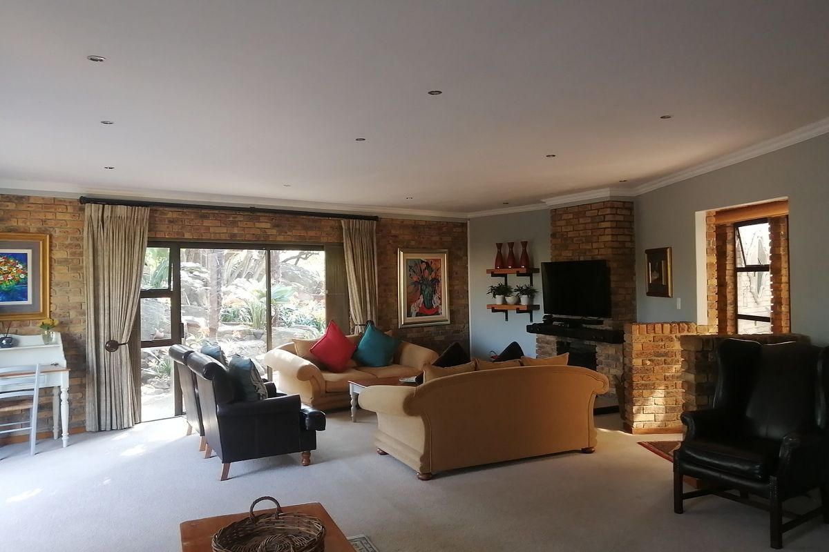 Spacious living room featuring an exposed brick wall, a brick fireplace, and large sliding glass doors providing natural light and garden access.