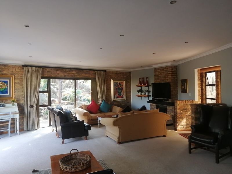 Spacious living room featuring an exposed brick wall, a brick fireplace, and large sliding glass doors providing natural light and garden access.
