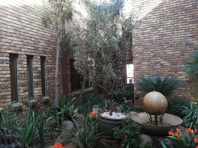A private courtyard garden featuring face brick walls, established landscaping, and a decorative stone water feature.