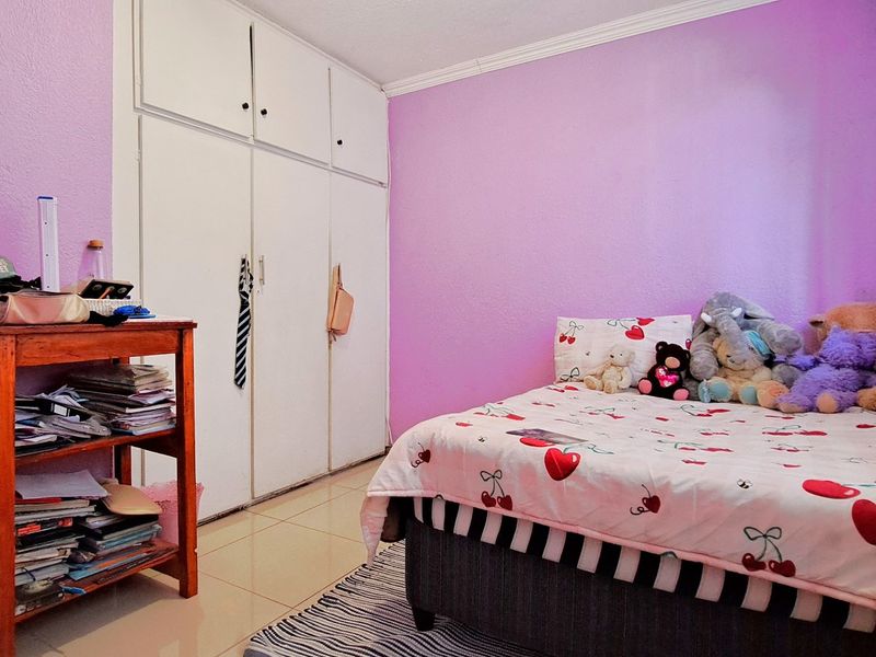 A bedroom featuring built-in cupboards, tiled flooring, and decorative cornice detailing.