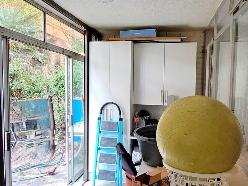 Enclosed patio or sunroom featuring tiled flooring, built-in storage cabinetry, and large sliding glass doors providing access to the outdoor area.