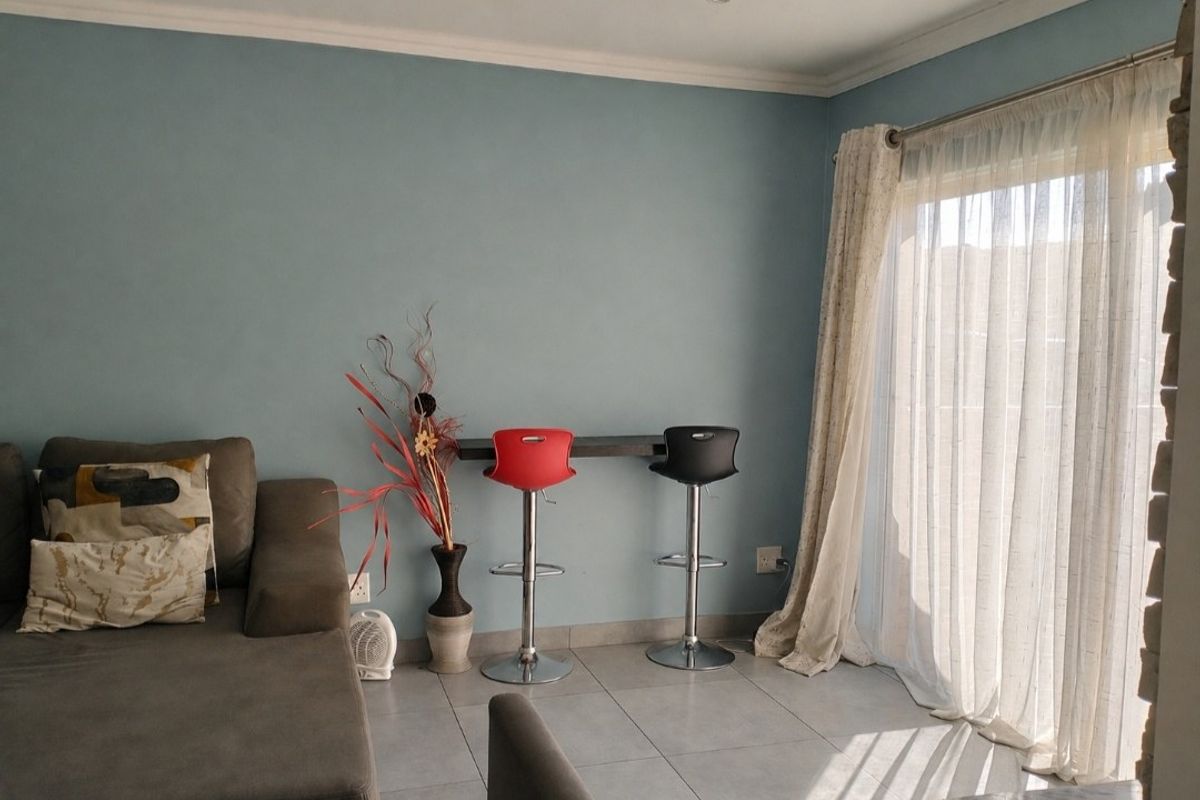 A living area featuring tiled flooring, a wall-mounted breakfast bar, and a sliding glass door providing natural light.