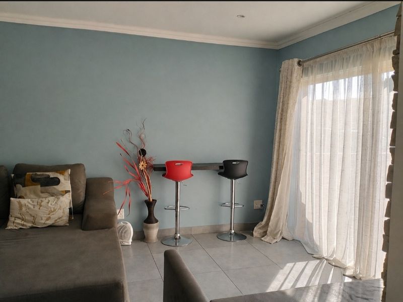 A living area featuring tiled flooring, a wall-mounted breakfast bar, and a sliding glass door providing natural light.
