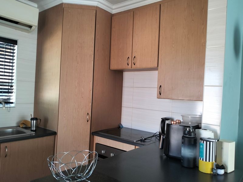A functional kitchen featuring wood-finish cabinetry, dark laminate countertops, a built-in oven and hob, and a tiled backsplash.