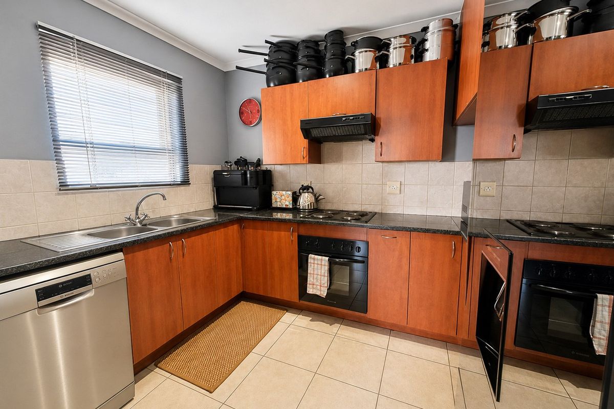 A functional kitchen featuring wood-tone cabinetry, granite countertops, tiled backsplash, and integrated appliances including an oven and hob.