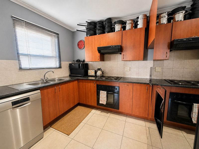 A functional kitchen featuring wood-tone cabinetry, granite countertops, tiled backsplash, and integrated appliances including an oven and hob.