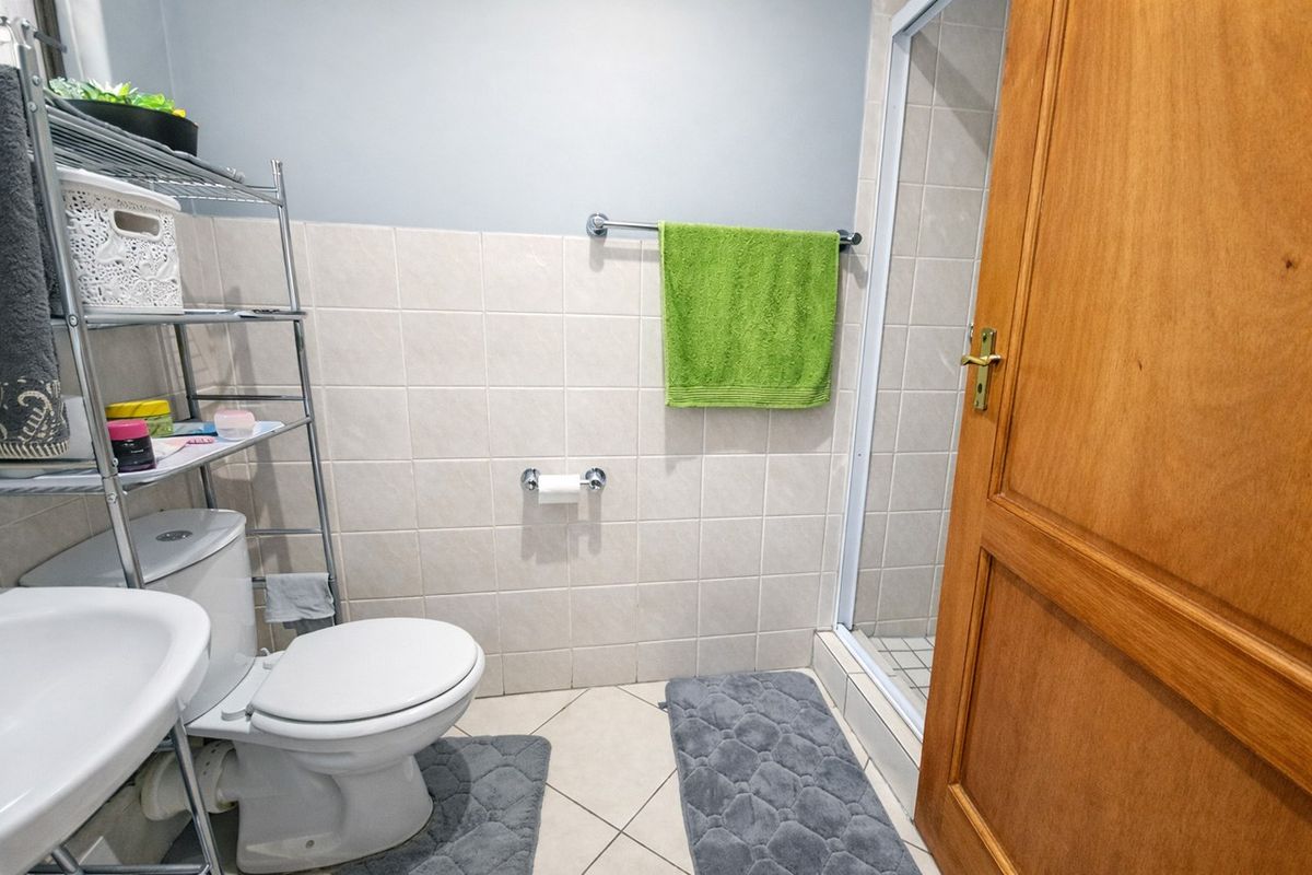A functional bathroom featuring a pedestal basin, toilet, and a separate shower enclosure with tiled finishes.