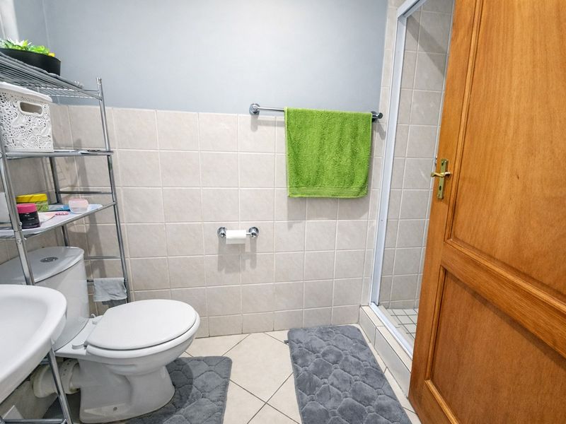 A functional bathroom featuring a pedestal basin, toilet, and a separate shower enclosure with tiled finishes.