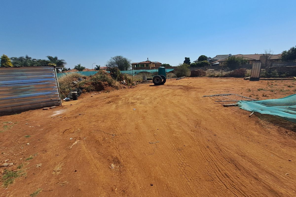 A vacant residential plot featuring a corrugated metal shed and basic wire fencing, offering a blank canvas for future development.