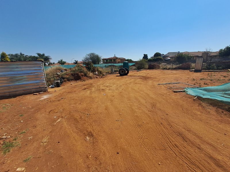 A vacant residential plot featuring a corrugated metal shed and basic wire fencing, offering a blank canvas for future development.