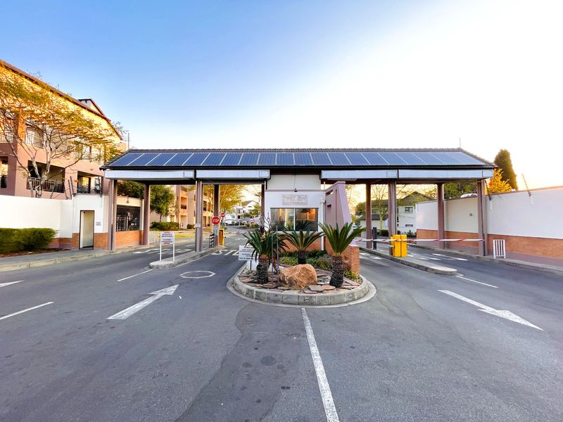 The secure entrance to the apartment complex features a manned guardhouse, boom gates, and solar-powered roofing for enhanced security and energy efficiency.