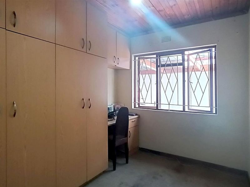 Bedroom featuring extensive built-in cabinetry, timber ceiling, and a window fitted with security bars.