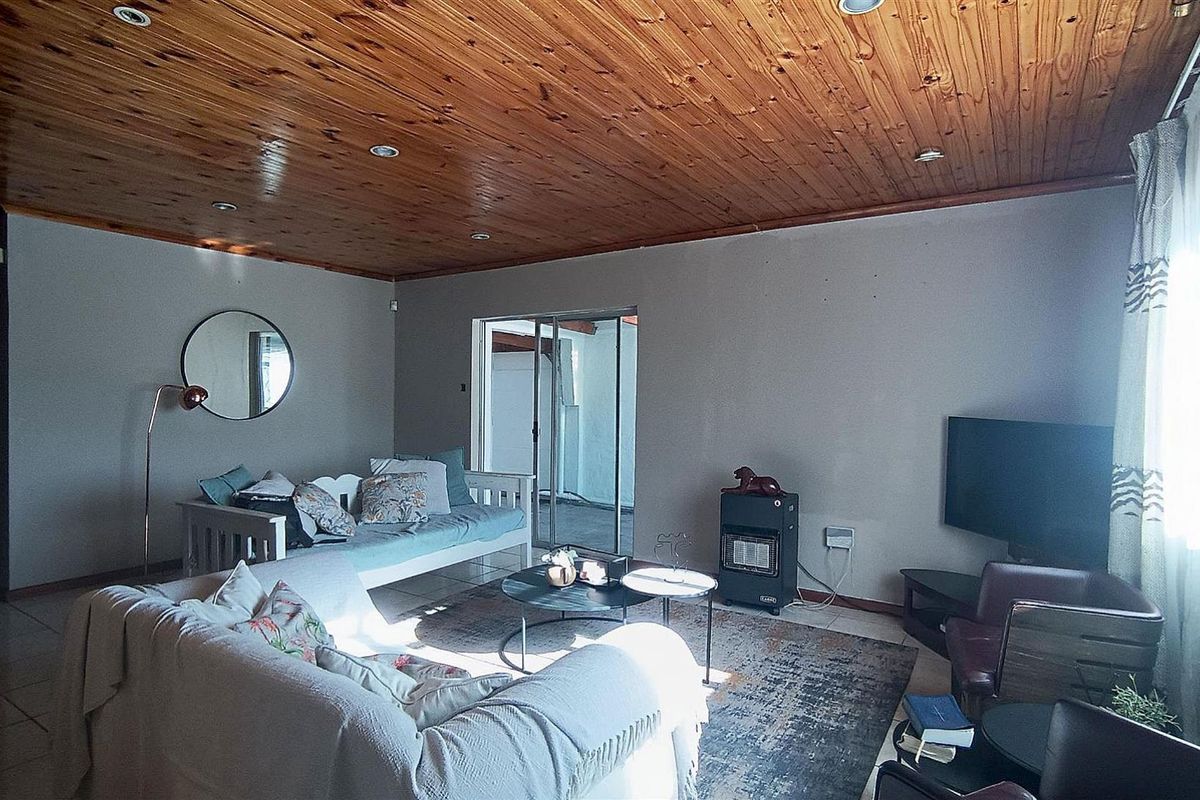 Spacious living room featuring a warm timber tongue and groove ceiling, tiled flooring, and direct access to an outdoor area through sliding glass doors.