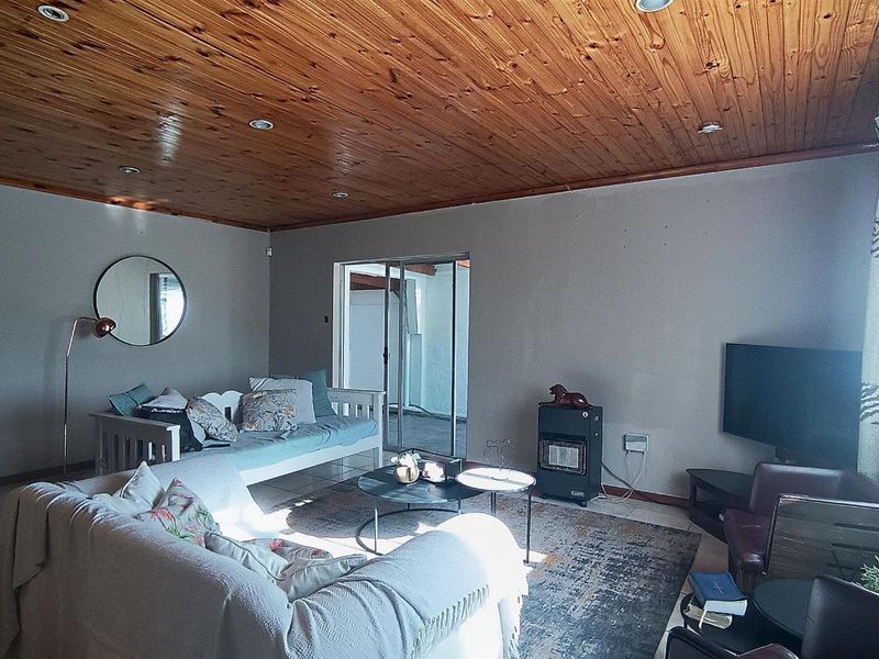 Spacious living room featuring a warm timber tongue and groove ceiling, tiled flooring, and direct access to an outdoor area through sliding glass doors.