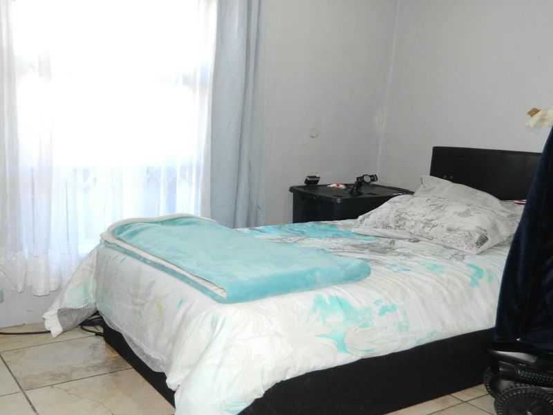 A bedroom featuring tiled flooring and a window with curtains.