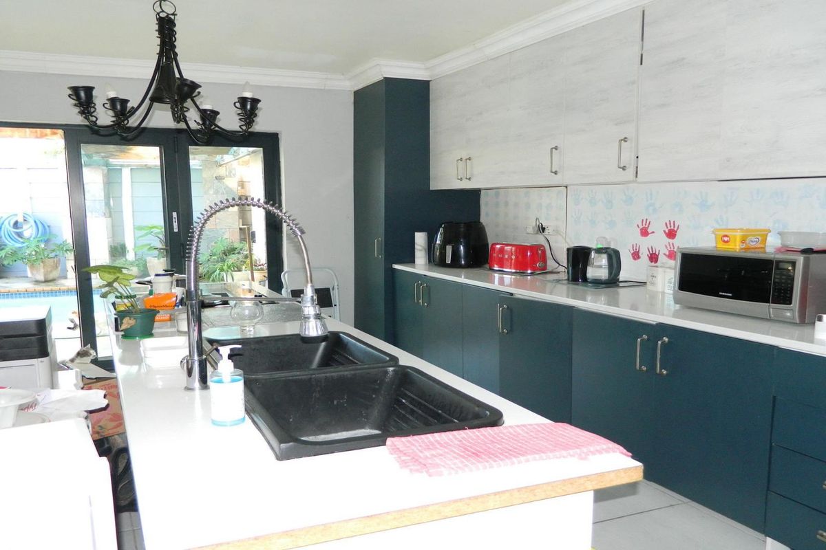 Modern kitchen featuring a central island with a double basin sink, stone countertops, two-tone cabinetry, and direct access to the outdoor patio area.