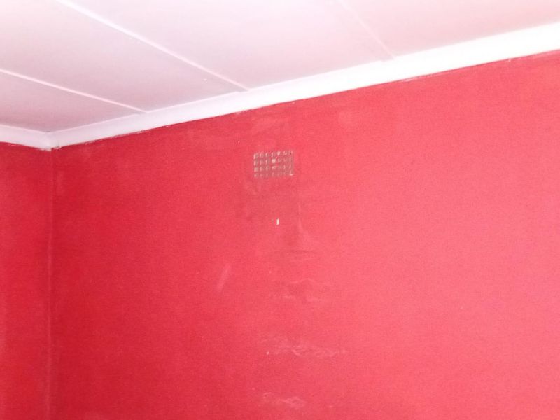 An empty room featuring red painted walls and a white ceiling with cornice detailing.