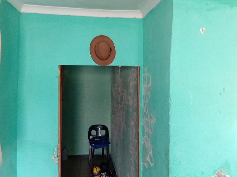 A narrow hallway space featuring painted walls with visible surface damage and wear, requiring cosmetic attention and repair.