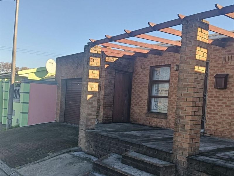 Front elevation of a face brick house featuring a timber pergola, paved entrance steps, and an attached garage.