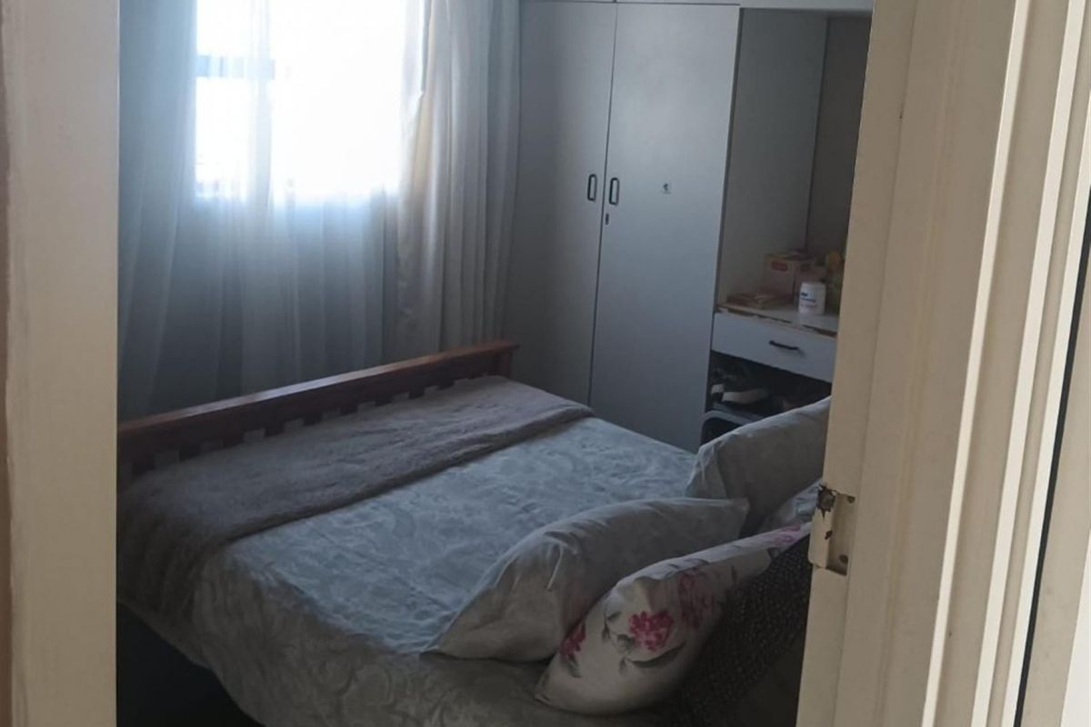 A functional bedroom featuring a built-in wardrobe with an integrated vanity unit and natural light from the window.