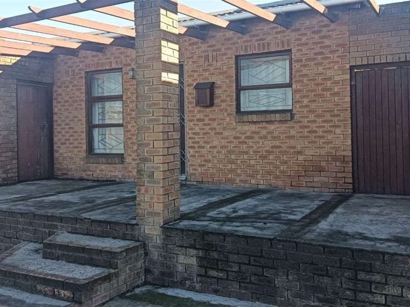 A covered brick patio area featuring a timber pergola, concrete flooring, and secure access points with security bars on the windows.