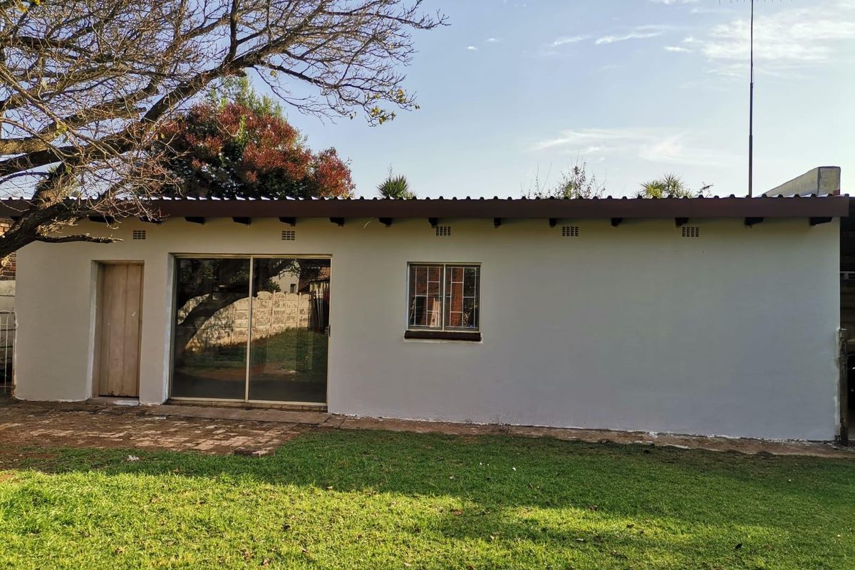 Rear exterior view of the property featuring a sliding glass door, a single window, and a paved patio area leading to the garden.
