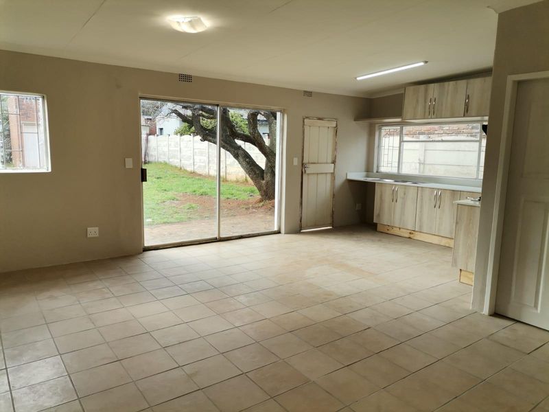 Open-plan living and kitchen area featuring tiled flooring, built-in cabinetry, and a sliding glass door providing direct access to the rear garden.