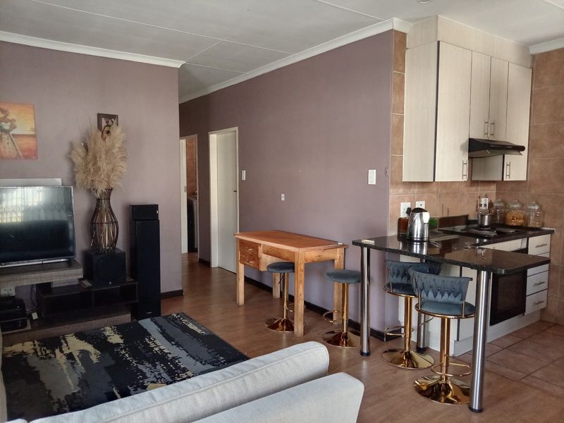 Open-plan living area featuring a kitchen with granite countertops, built-in cabinetry, and a breakfast bar, seamlessly flowing into the lounge space.
