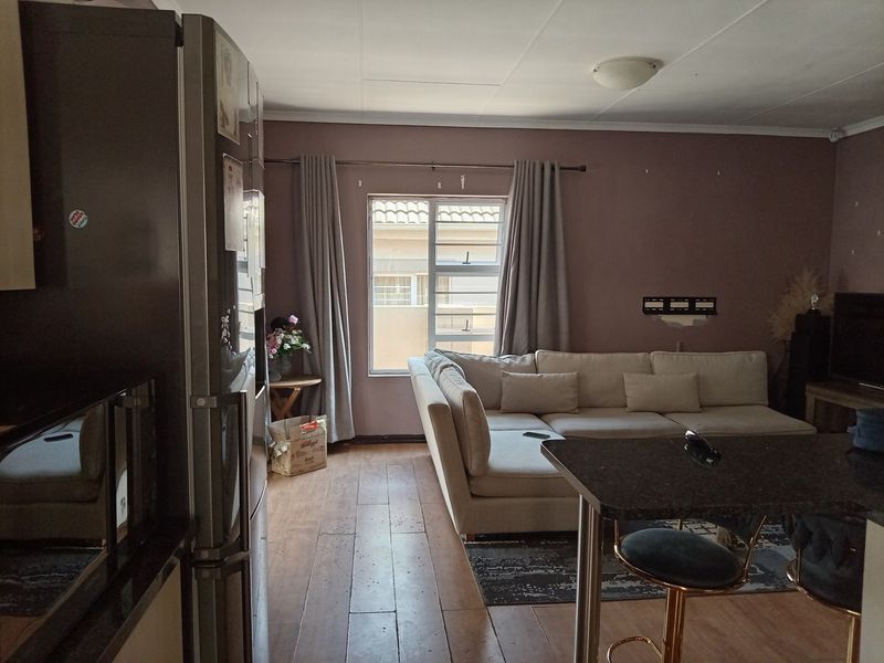Open plan living area featuring laminate flooring and a granite breakfast bar, connecting the kitchen and lounge space in a functional townhouse layout.