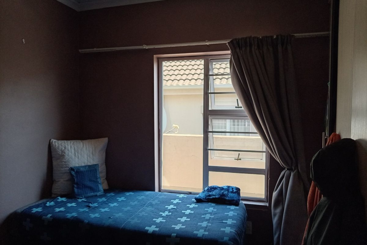 A bedroom featuring a window with security bars, a curtain rod, and built-in wardrobe storage.