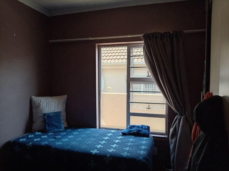 A bedroom featuring a window with security bars, a curtain rod, and built-in wardrobe storage.
