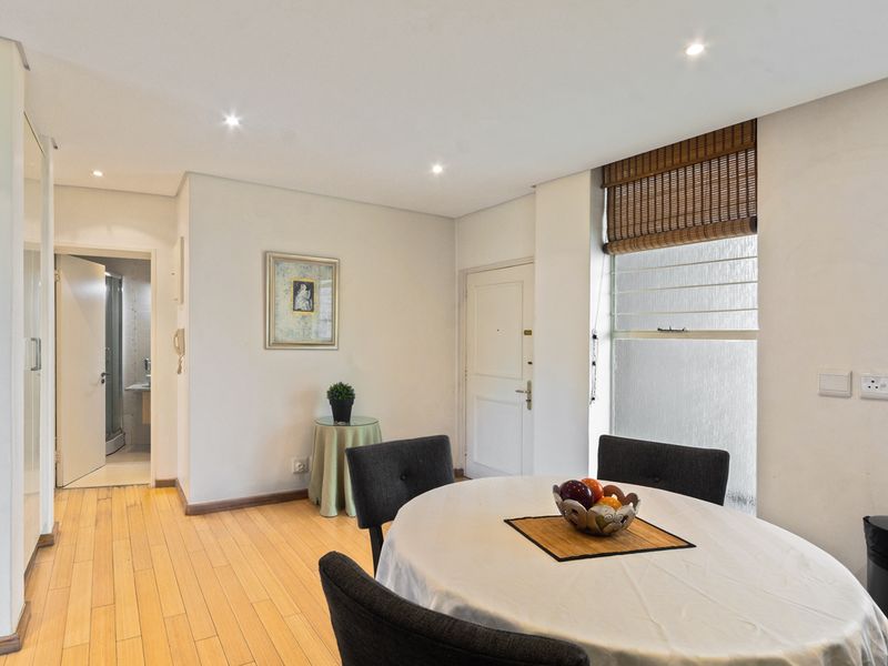 A bright living area featuring timber flooring, recessed downlighting, and a window with a bamboo roller blind, providing a clean and functional space.