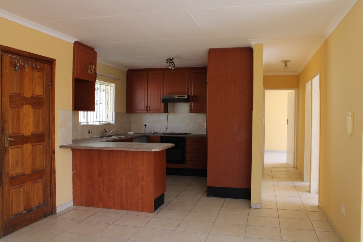A functional kitchen featuring laminate cabinetry, built-in oven, extractor fan, and tiled flooring, offering a practical layout for renovation or modernization.