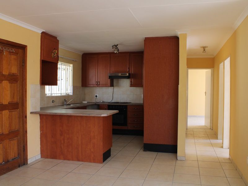 A functional kitchen featuring laminate cabinetry, built-in oven, extractor fan, and tiled flooring, offering a practical layout for renovation or modernization.