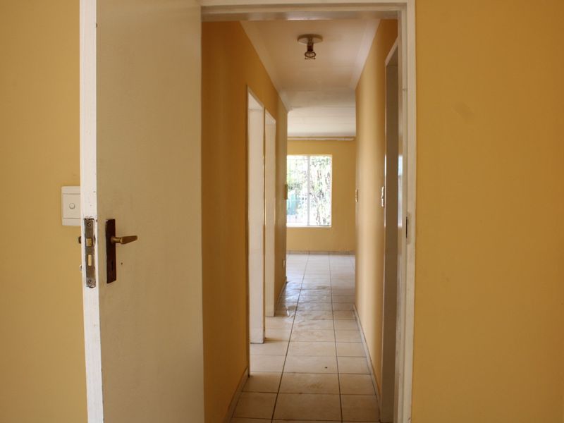 A vacant hallway with tiled flooring and yellow painted walls, providing access to adjacent rooms within the townhouse.