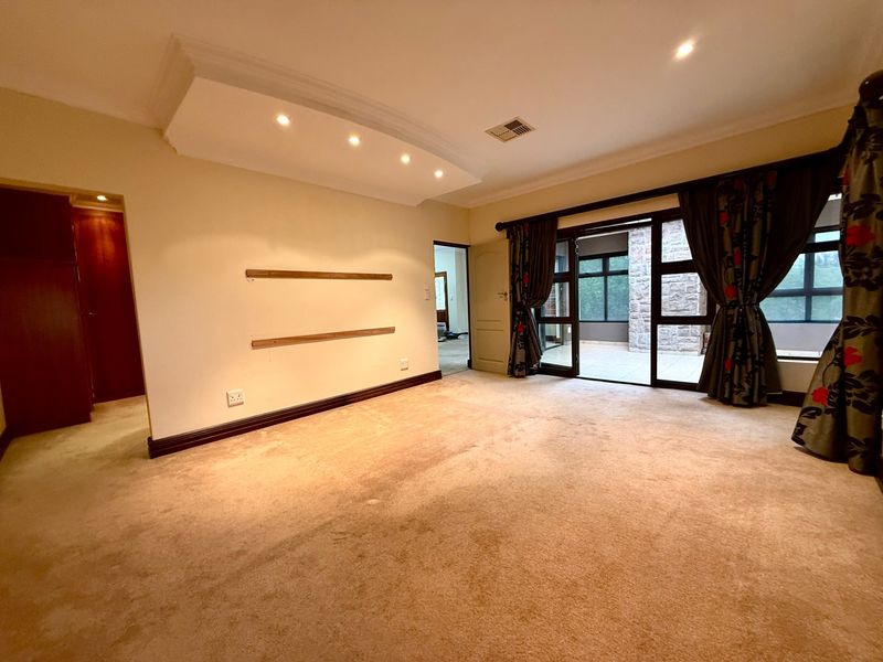 Spacious living room featuring recessed ceiling lighting, carpeted flooring, and large sliding glass doors providing access to an outdoor patio area.