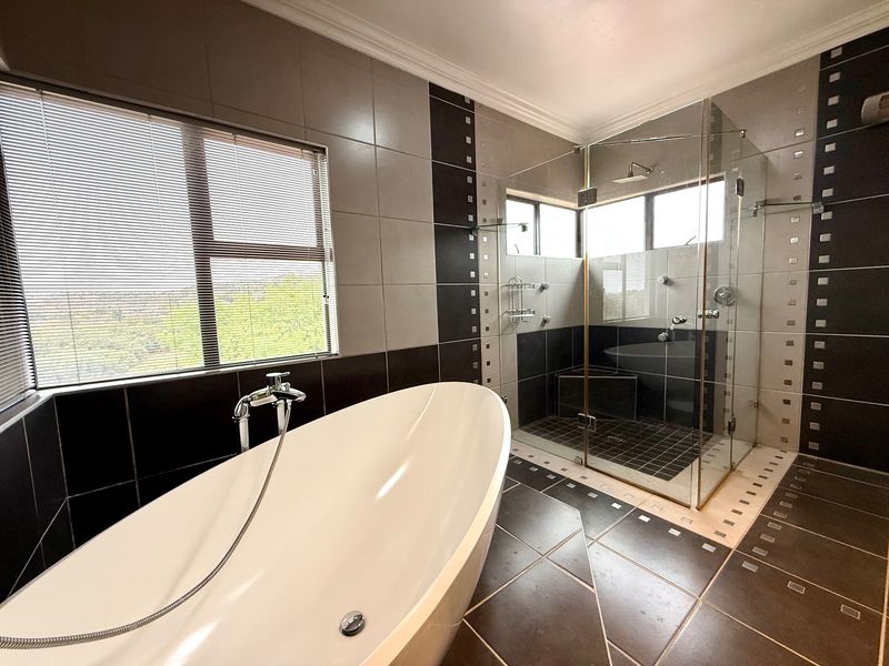 Modern bathroom featuring a sleek freestanding bathtub, a spacious glass-enclosed shower, and contemporary tiled finishes throughout.