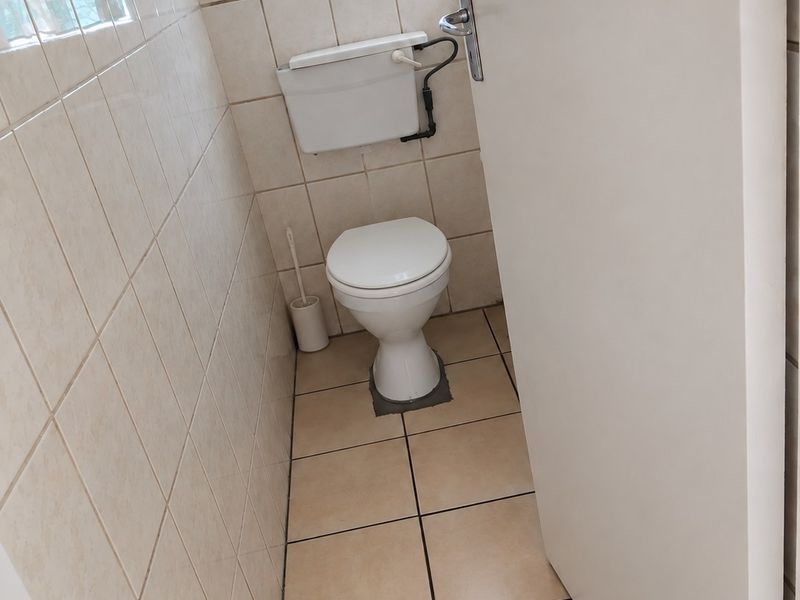 A compact, tiled bathroom featuring a standard toilet with a wall-mounted cistern and neutral ceramic finishes.