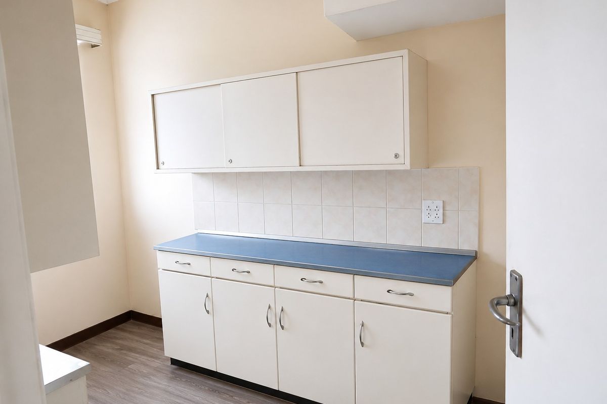A clean, empty kitchen area featuring white cabinetry, a blue laminate countertop, tiled backsplash, and wood-look laminate flooring.