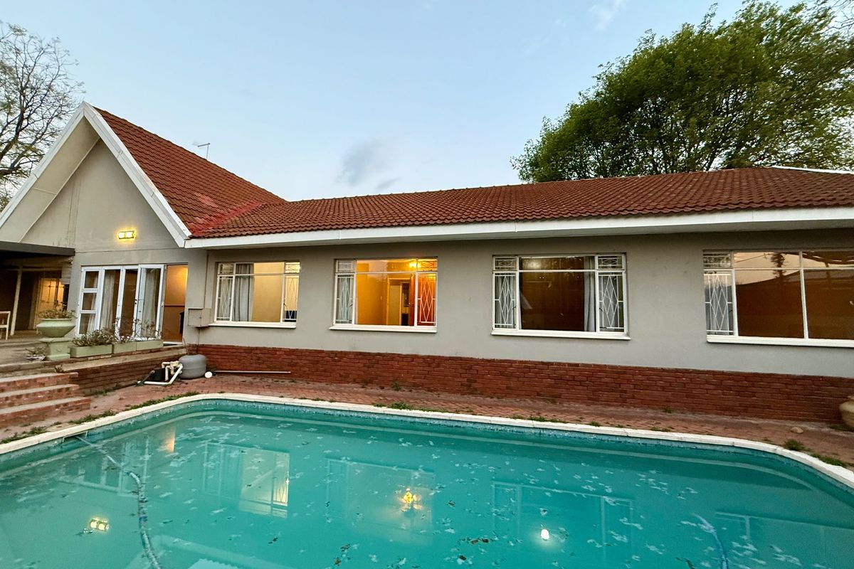 Rear view of the house featuring a swimming pool, paved surround, and traditional terracotta roof tiles with a brick and plaster facade.