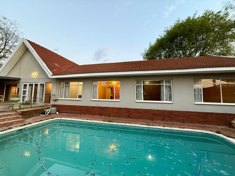 Rear view of the house featuring a swimming pool, paved surround, and traditional terracotta roof tiles with a brick and plaster facade.
