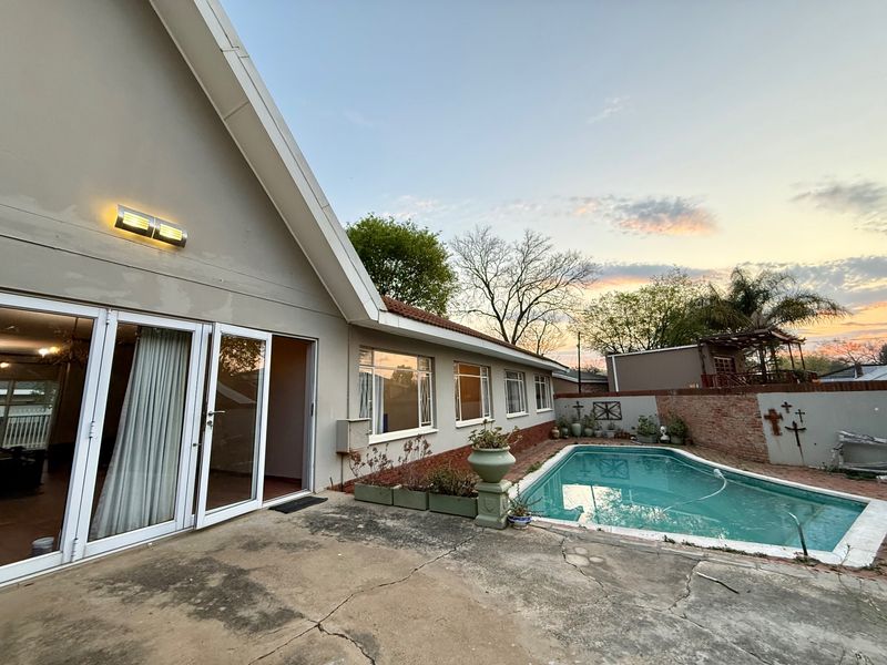 Rear exterior view featuring a swimming pool, concrete patio area, and sliding glass doors providing access to the home's interior.